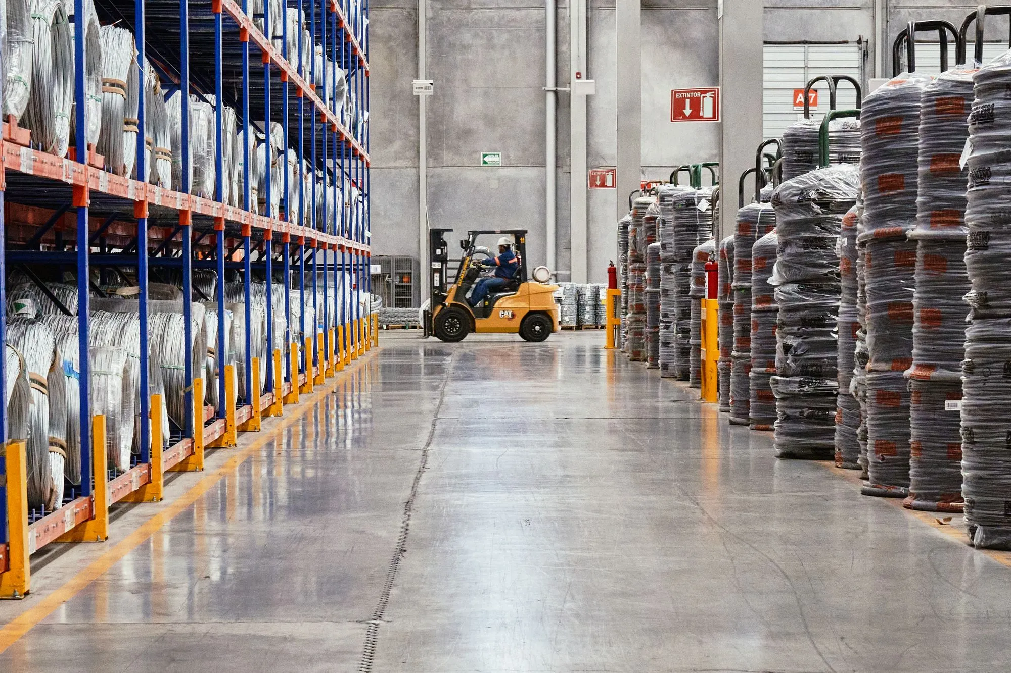 Pasillo de una bodega industrial con racks y montacargas