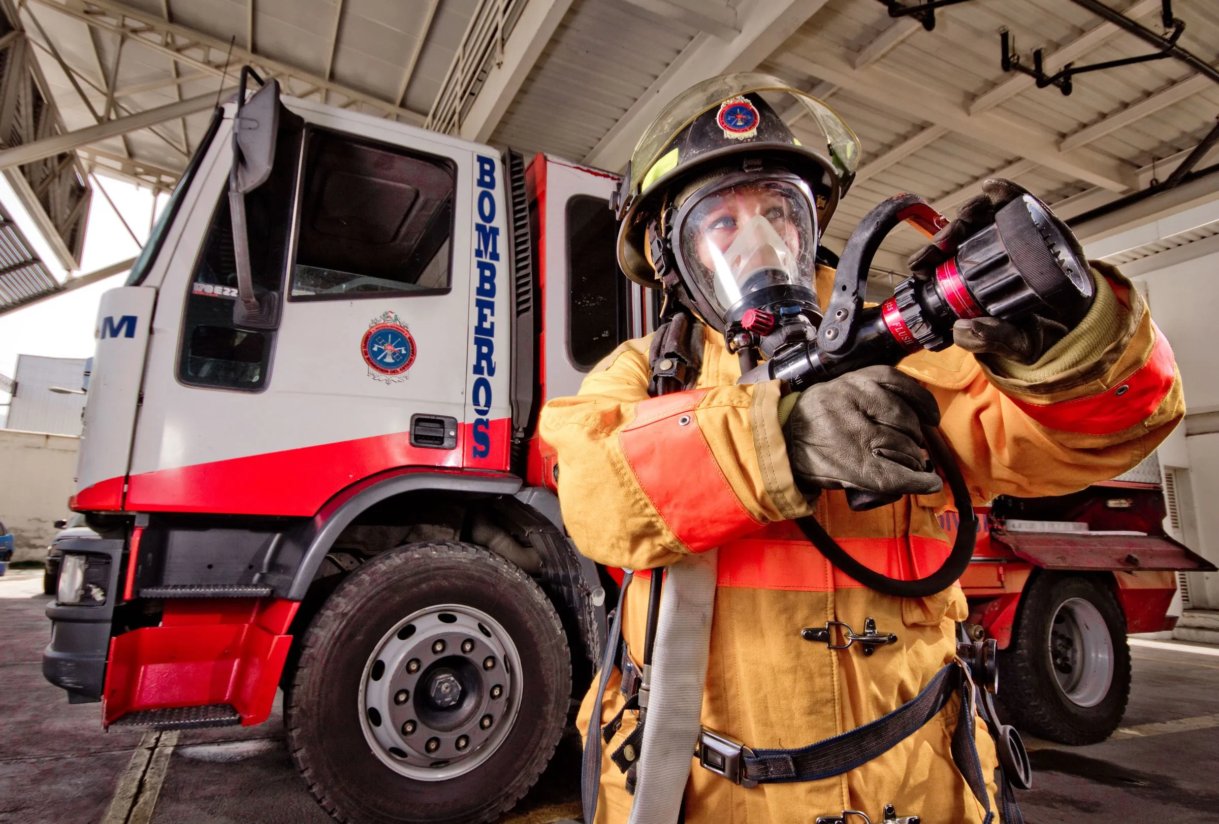 Bombero con traje estructural y equipo de respiración autónoma frente a una unidad de emergencia